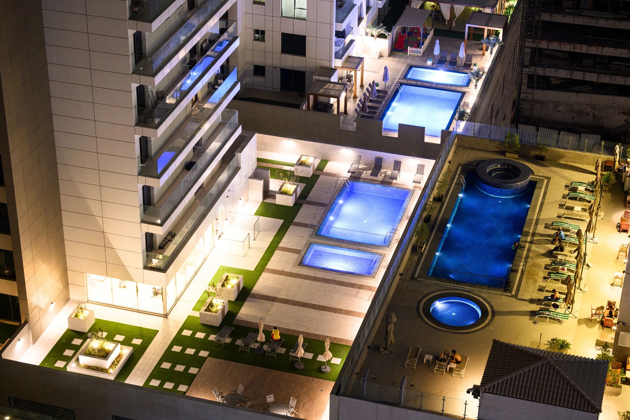 Luxury rooftop pools and lounge areas in Dubai apartment building at night